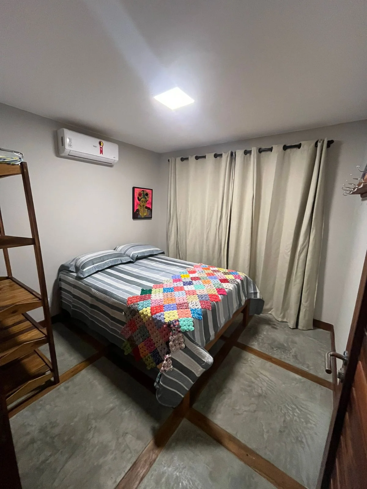 Quarto com cama de casal e cortina clara.
